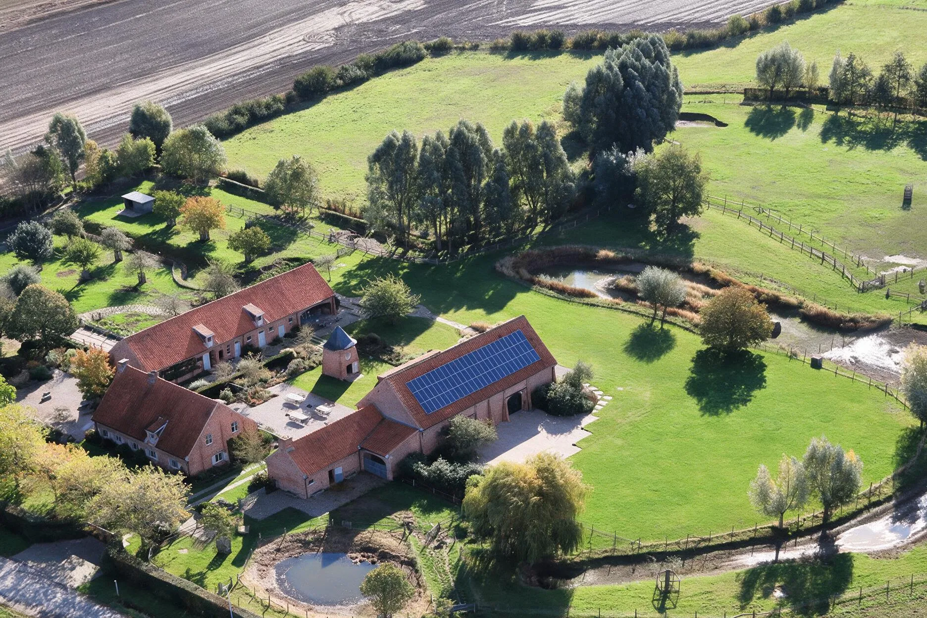 Zomerse luchtfoto van het domein Speghelhof met hoeve, feestschuur en vijver